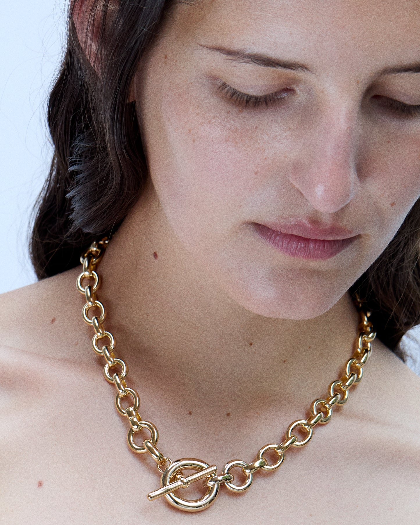 Model wearing Laura Lombardi gold Portrait Necklace with toggle clasp facing front.