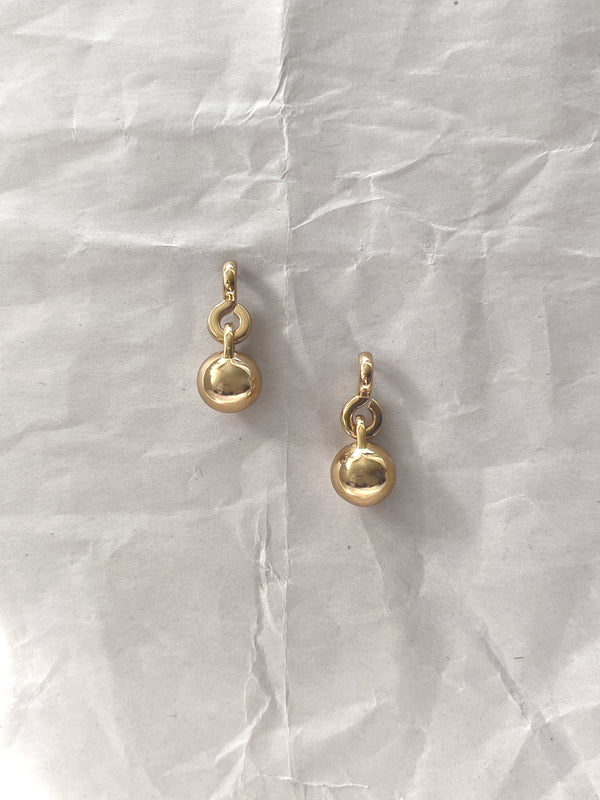 Laura Lombardi gold Gioca drop earrings on a white paper background.