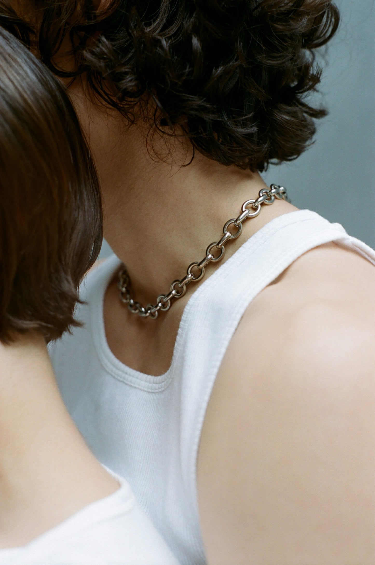 Person wearing the Laura Lombardi Silver Portrait chain necklace with a white tank top.