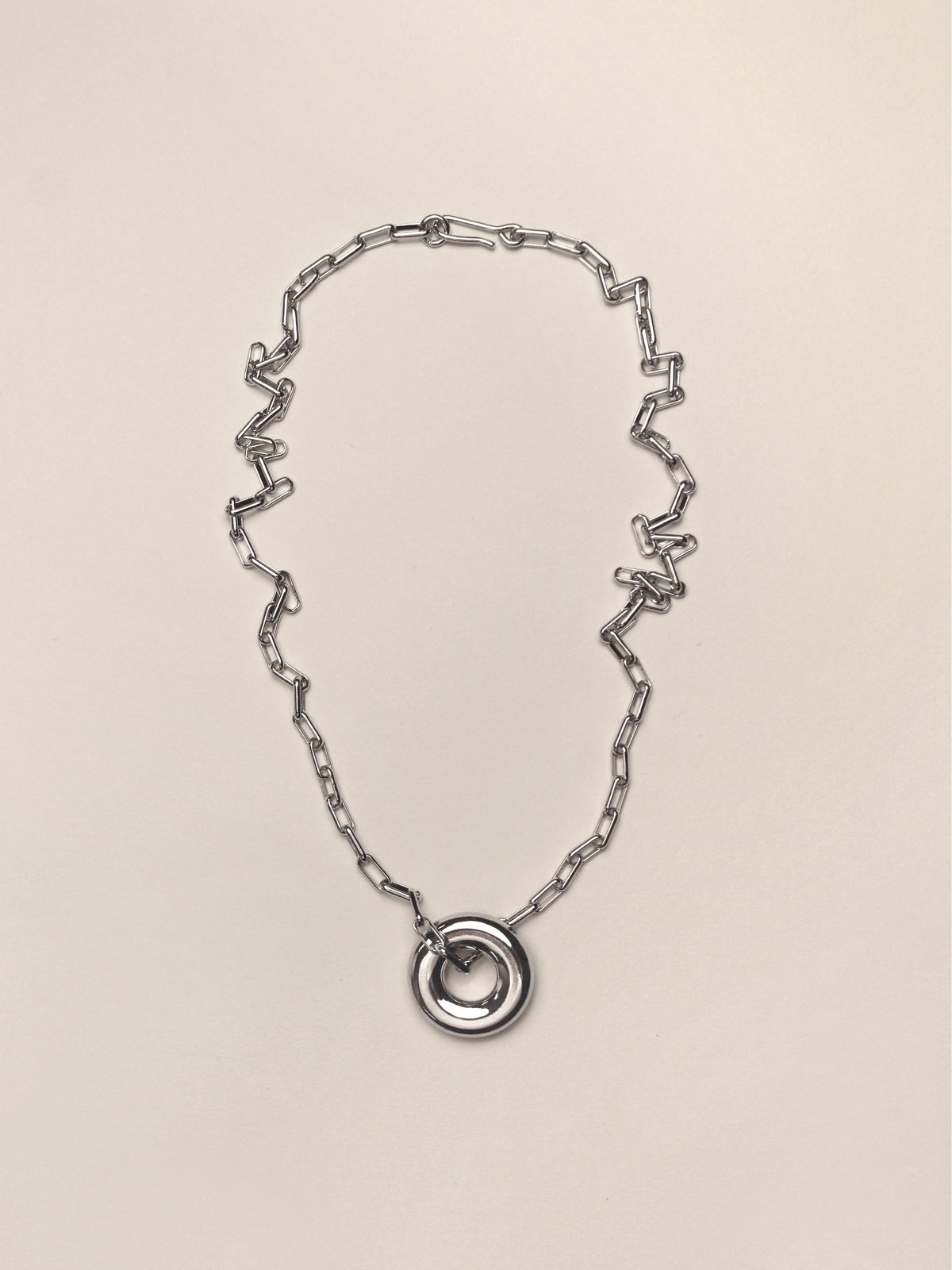 Silver Single Moneta necklace with a round pendant on a silver chain on a neutral colored background