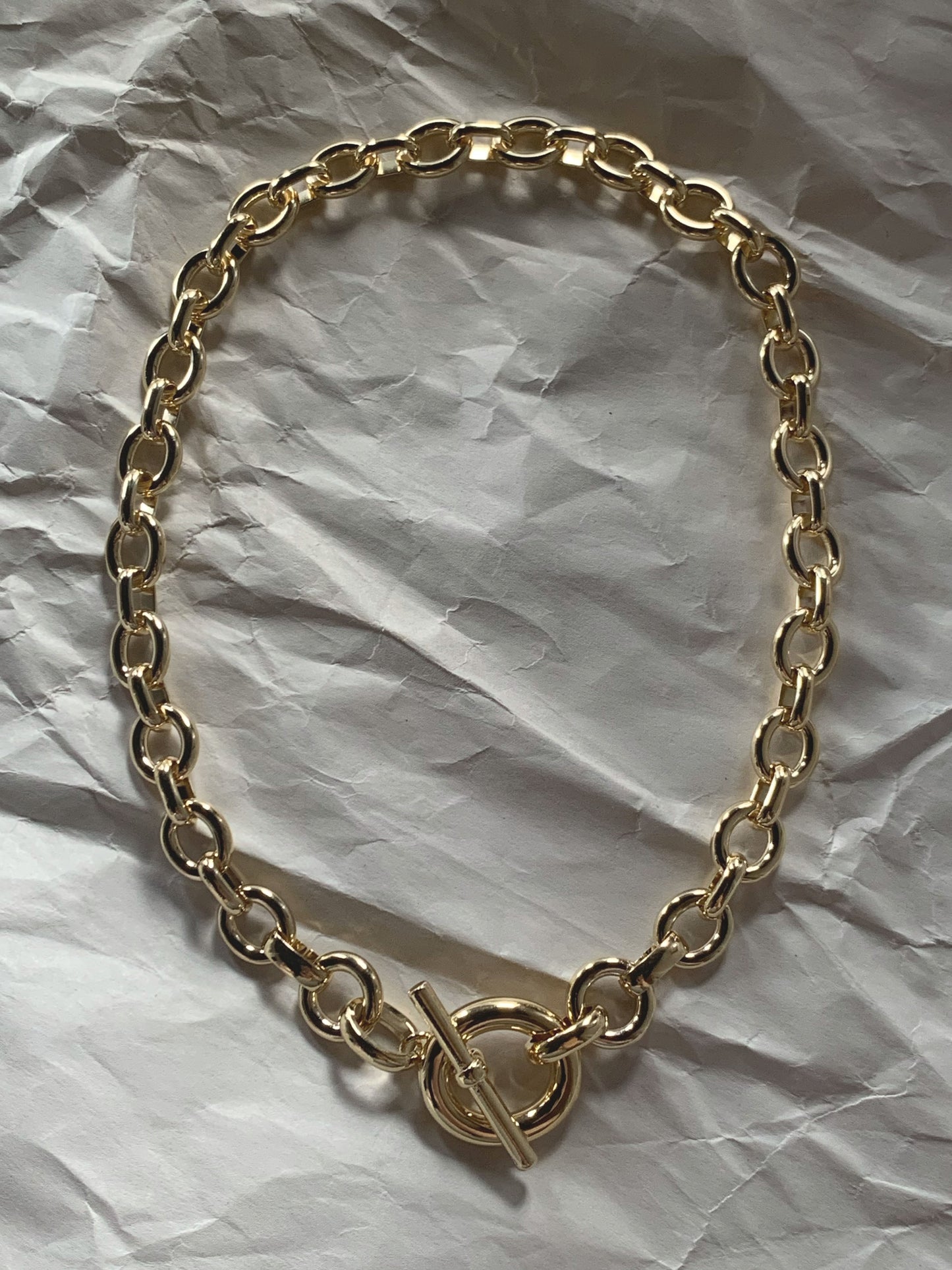 Silver chain necklace with a toggle clasp laid flat on a paper background.