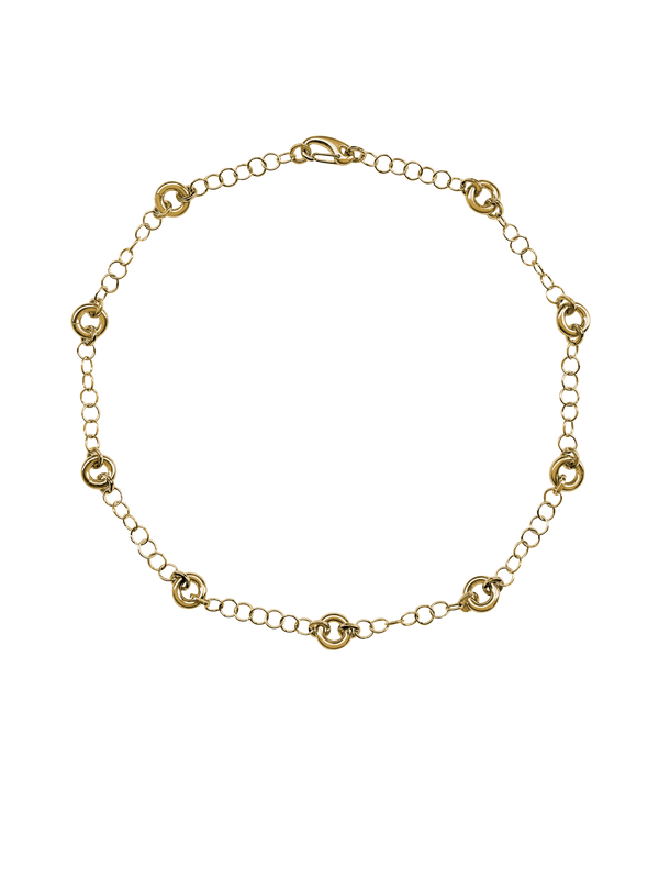 The Astra Necklace, a delicate cable chain with circular link accents in gold.