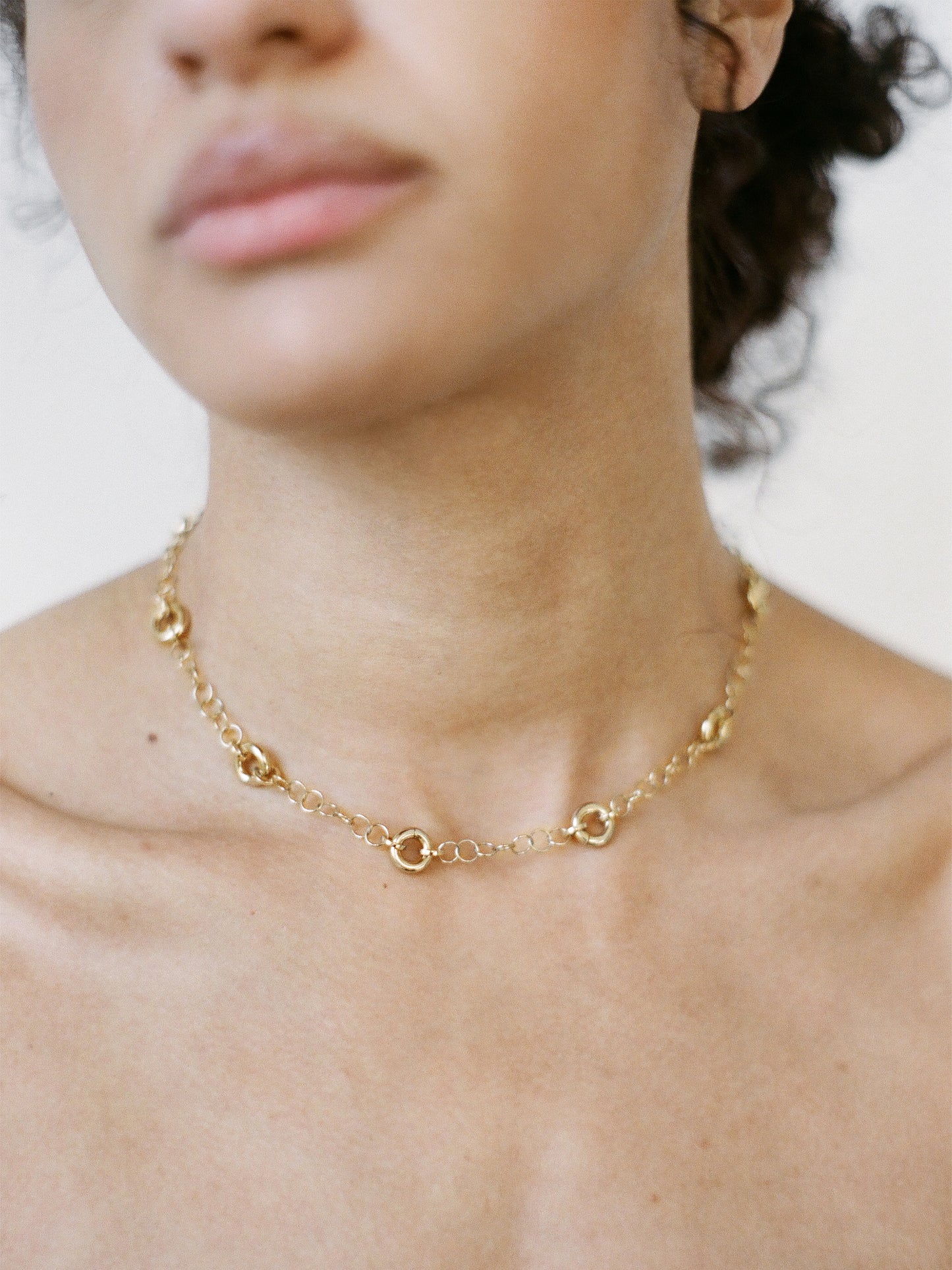 Model wearing the Astra Necklace, a delicate cable chain with circular link accents.