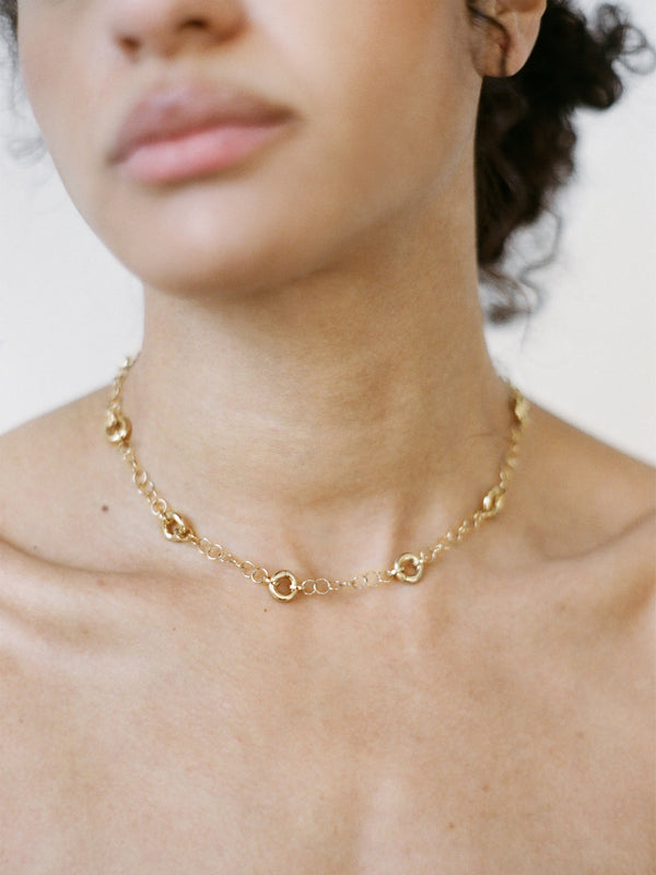Model wearing the Astra Necklace, a delicate cable chain with circular link accents.