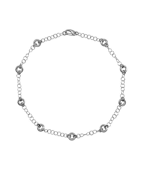 The Astra Necklace, a delicate cable chain with circular link accents in silver.