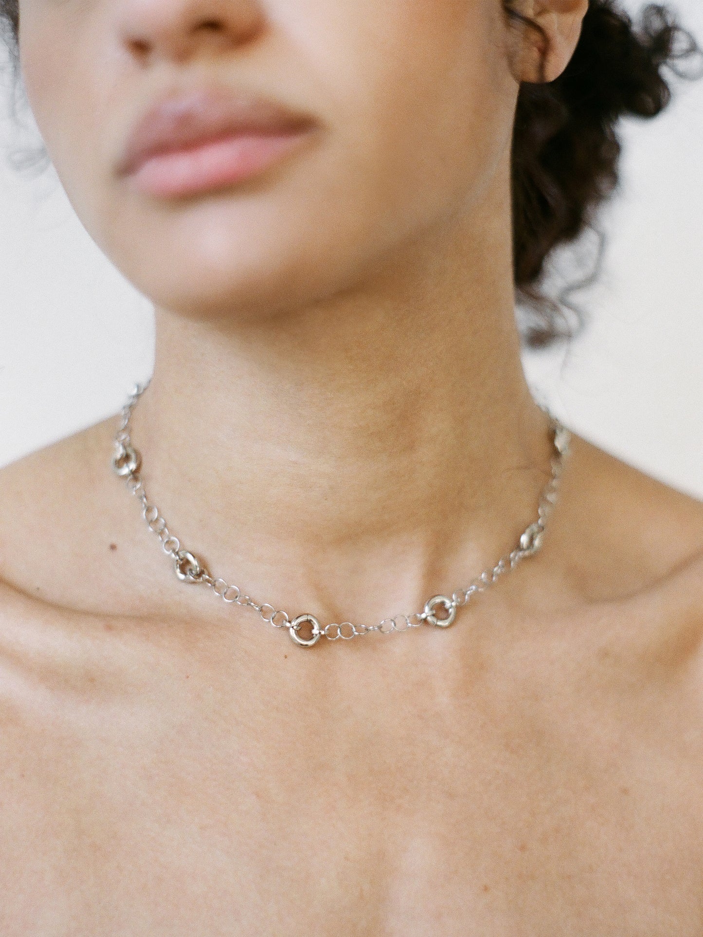Model wearing the Astra Necklace, a silver delicate cable chain with circular link accents.