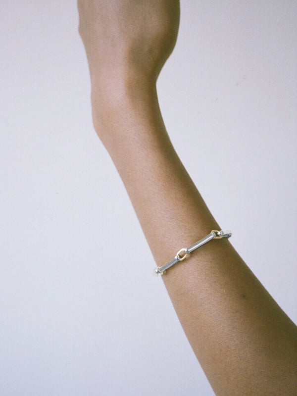 A two-tone chain link bracelet featuring silver-toned rectangular links and gold-toned square accents, worn on model against a neutral background.