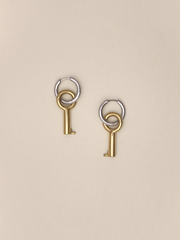Laura Lombardi Two Tone Entra Earrings, a pair of petite silver hoop earrings with dangling gold key charms, shown on a neutral background.