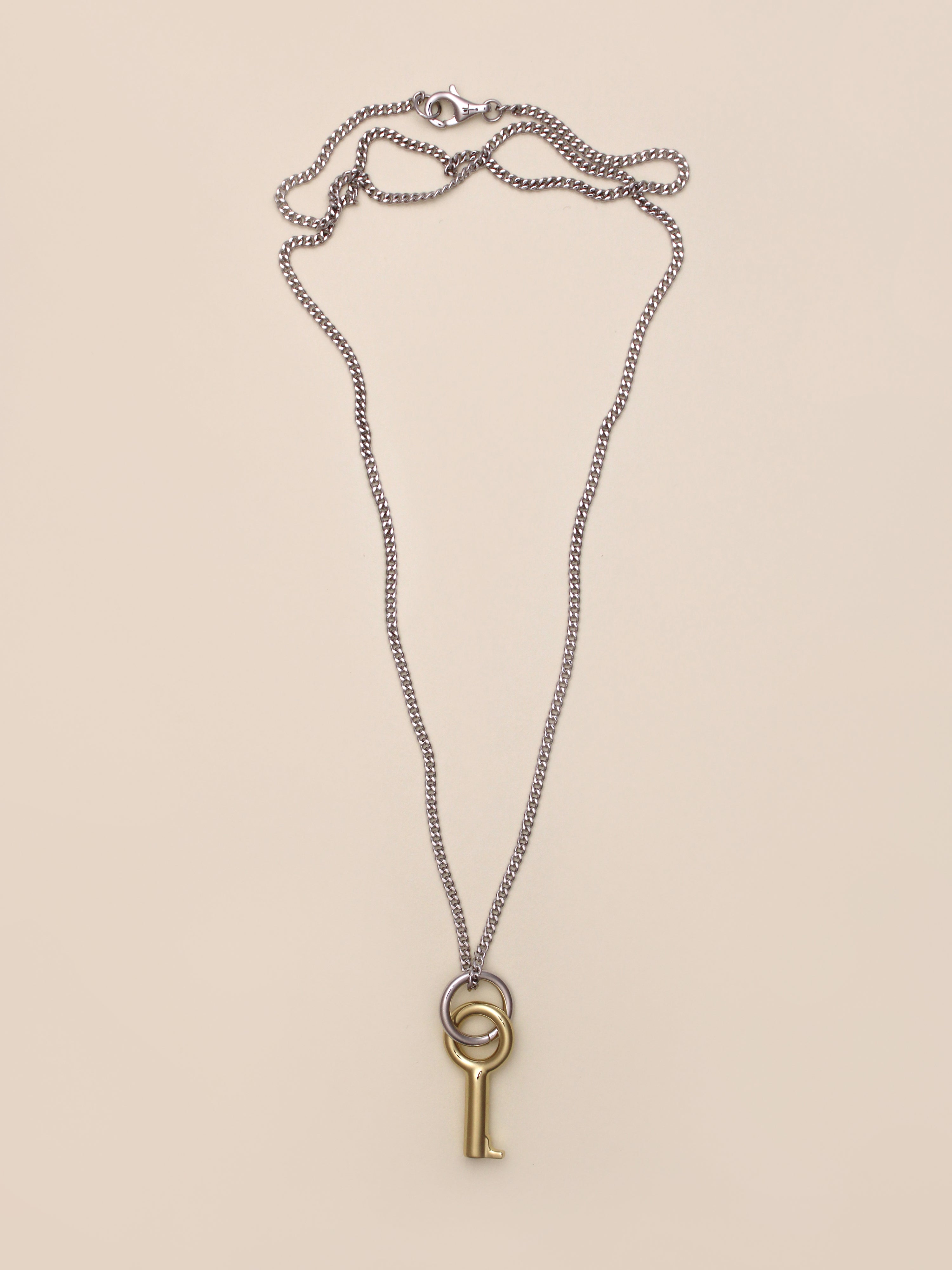 Laura Lombardi Two Tone Entra Necklace, a silver chain necklace featuring a gold key-shaped pendant on a small silver ring, displayed on a neutral background.