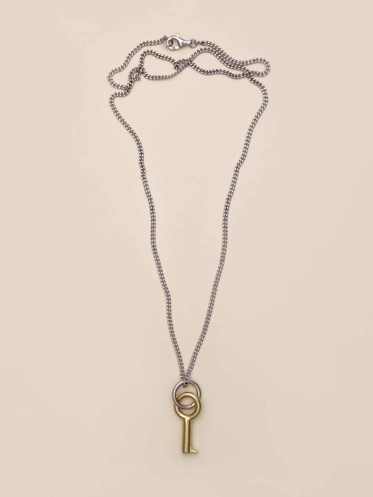 Laura Lombardi Two Tone Entra Necklace, a silver chain necklace featuring a gold key-shaped pendant on a small silver ring, displayed on a neutral background.