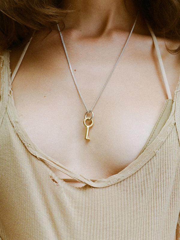 Model wearing Laura Lombardi Two Tone Entra Necklace, gold key charm strung on a silver chain.