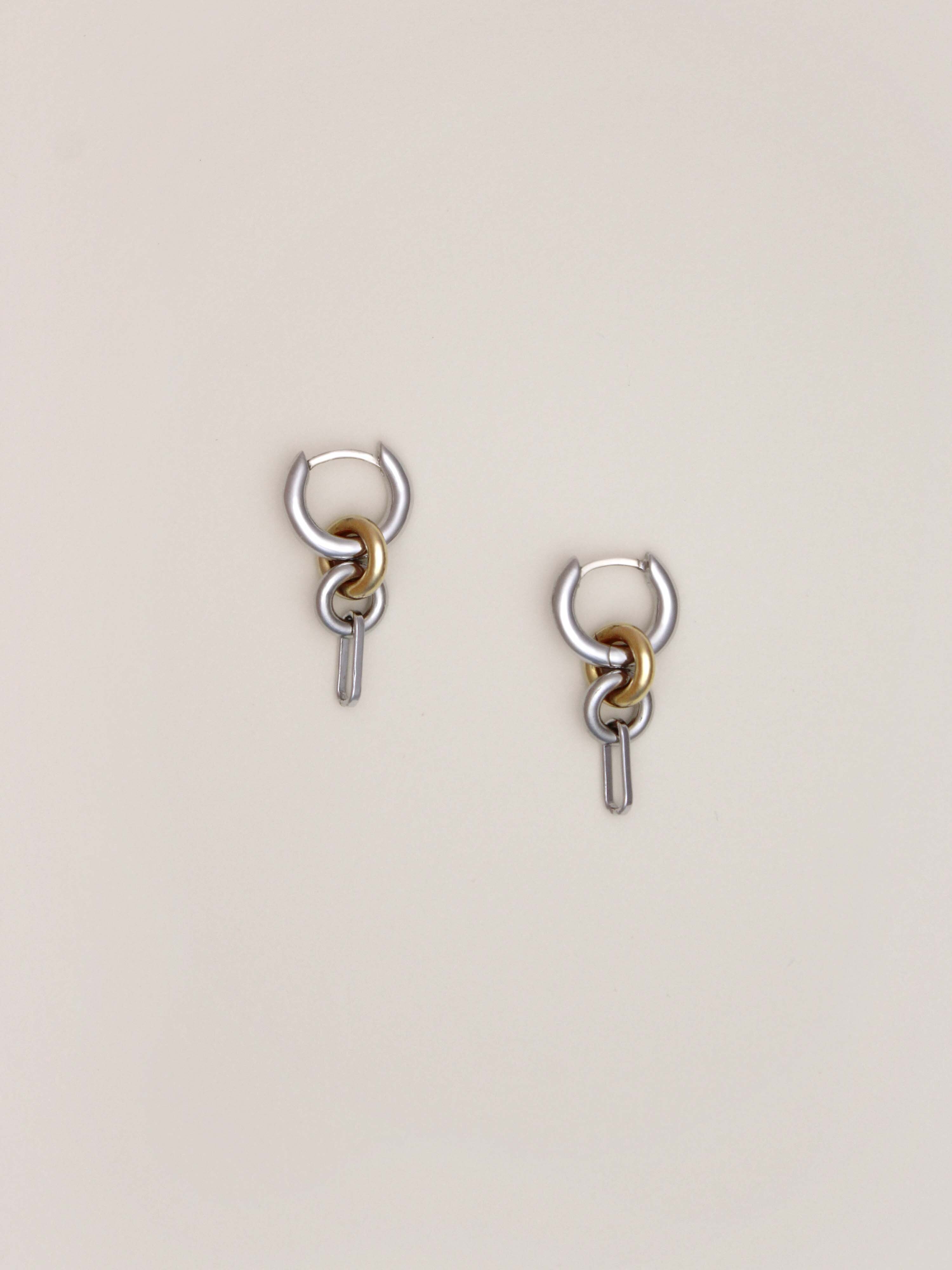 A pair of Two Tone Frena Earrings, silver hoop earrings with a dangling gold and silver chain link design, shown on a neutral background.