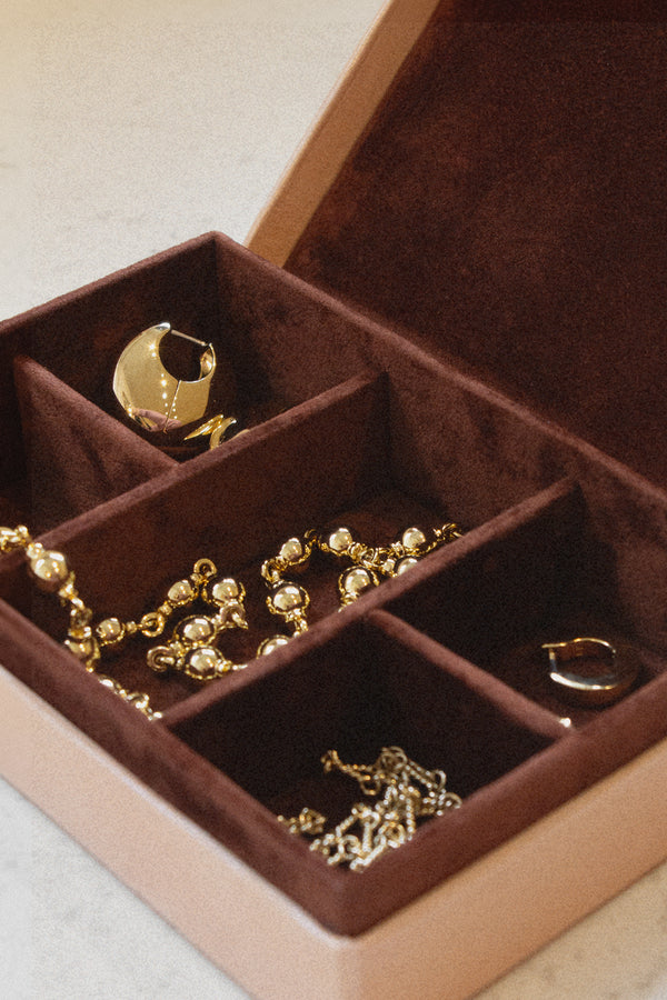 Laura Lombardi beige jewelry box with brown plush lining with gold necklaces and earrings inside.