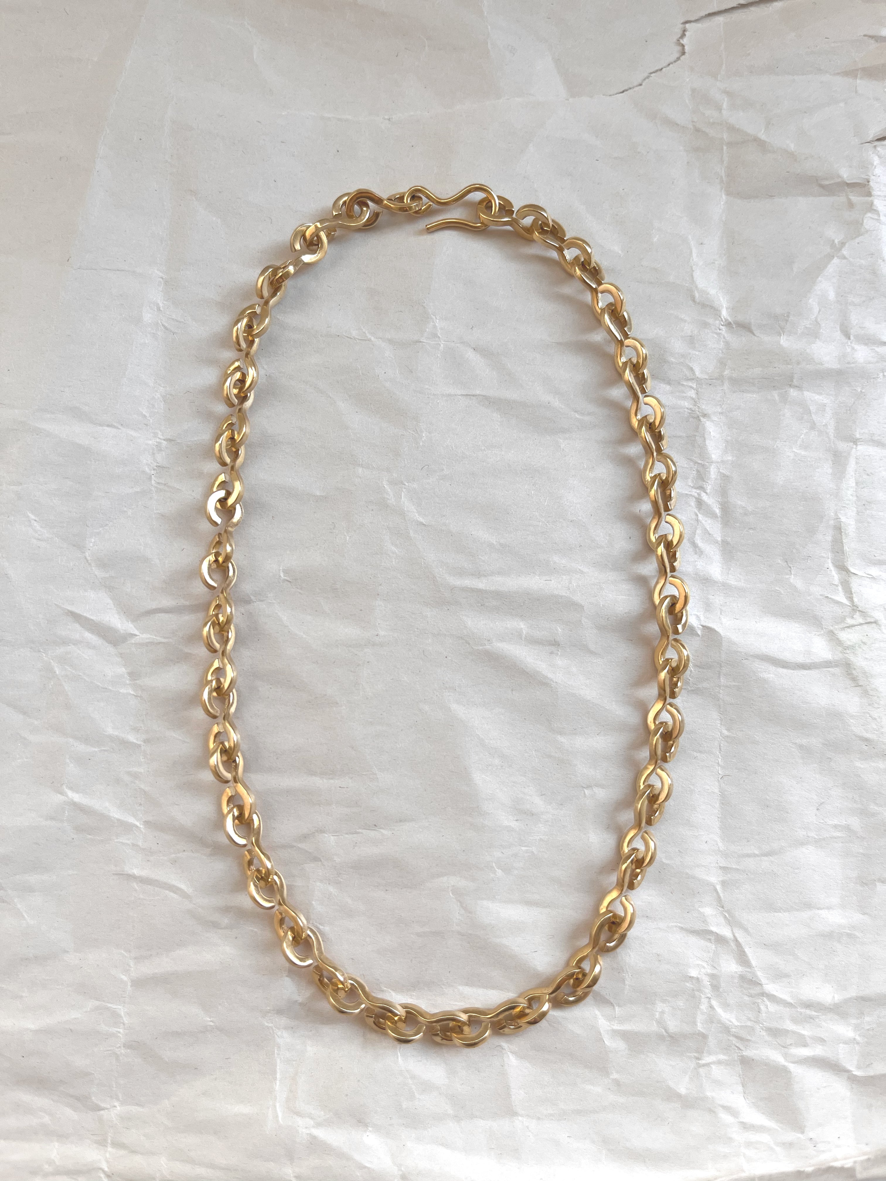 Laura Lombardi gold Nuova chain necklace on a white paper background.