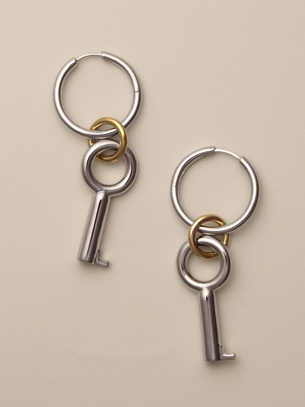 The Two Tone Permesso Earrings, a pair of silver hoop earrings with key-shaped charms and small gold rings connecting the hoops, shown on a neutral background.