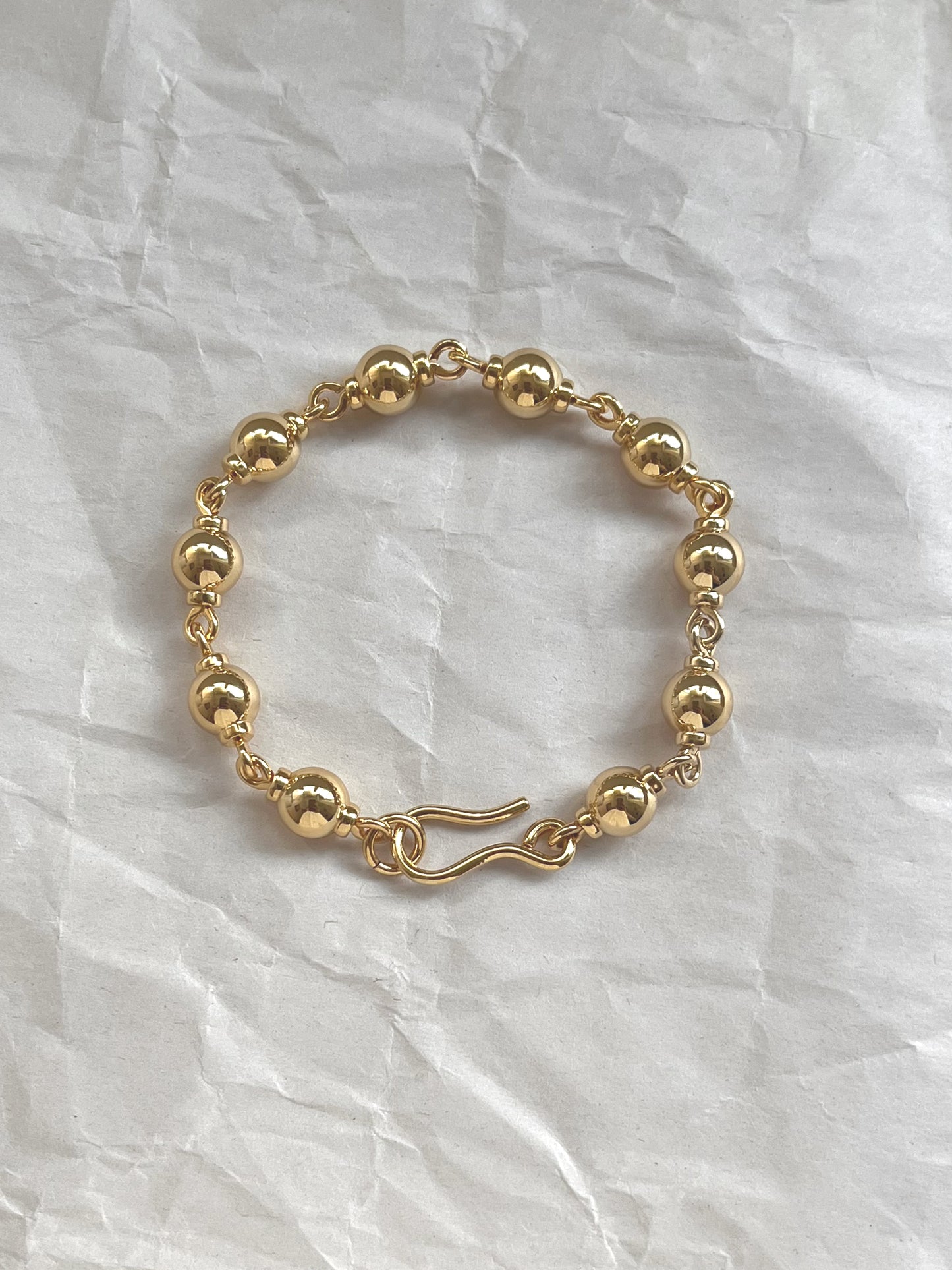 Laura Lombardi gold Suona beaded bracelet on a white paper background.