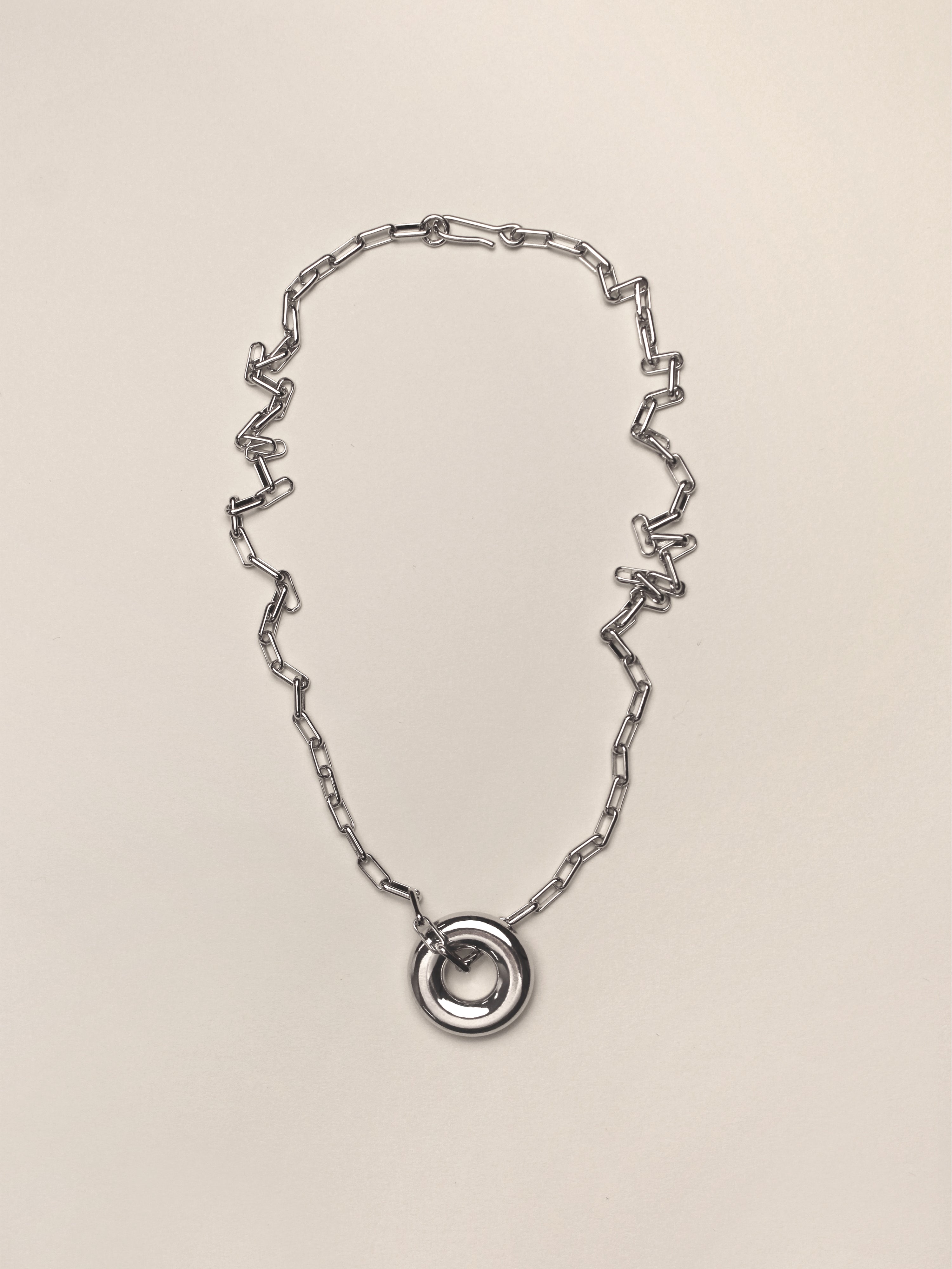 Silver Single Moneta necklace with a round pendant on a silver chain on a neutral colored background