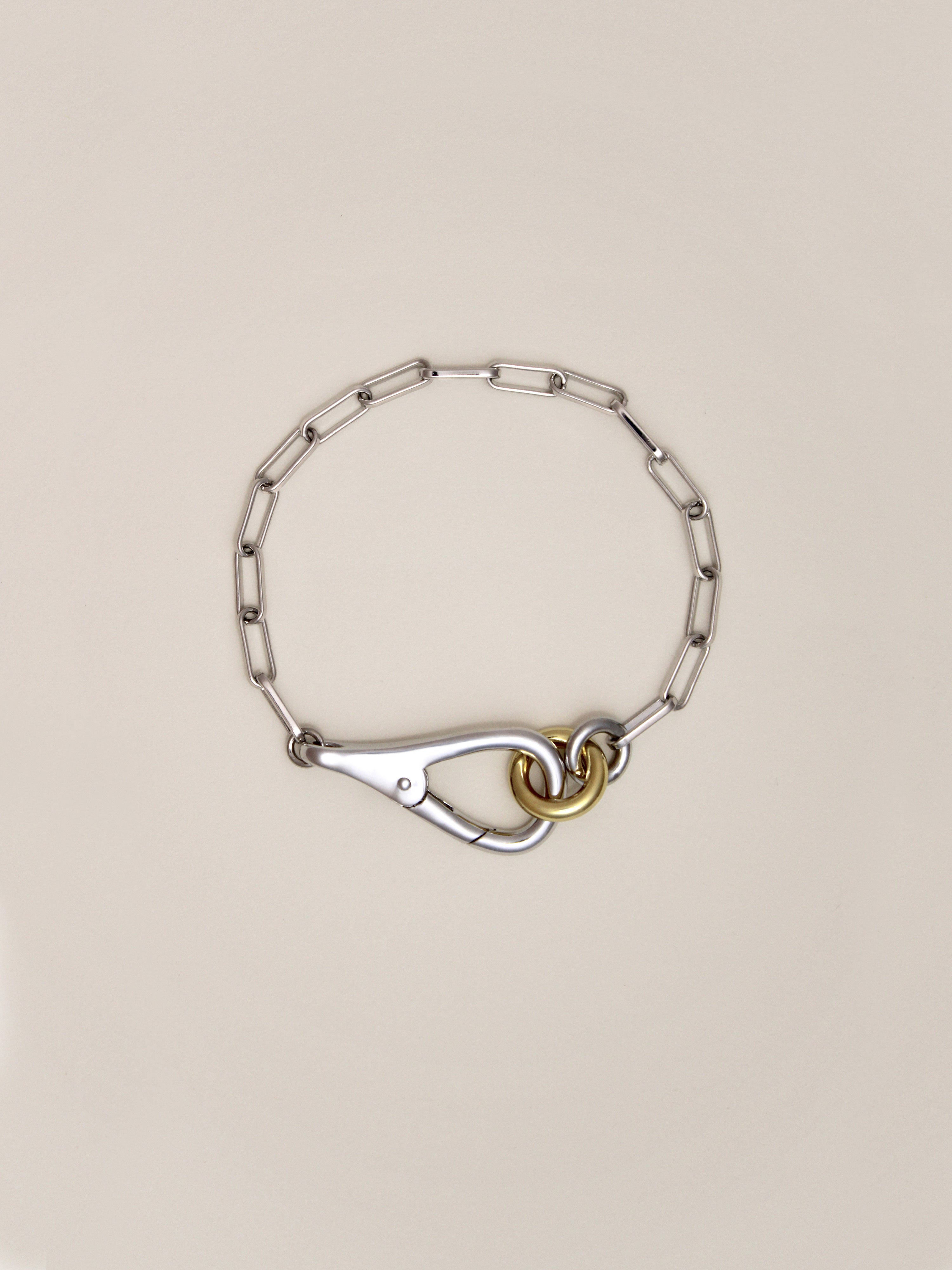 Two Tone Frena Bracelet, a silver-toned chain bracelet with a silver toggle clasp and gold jump ring, displayed on a neutral background.