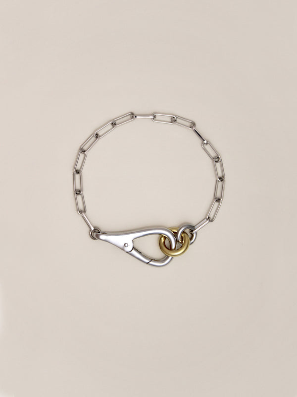 Two Tone Frena Bracelet, a silver-toned chain bracelet with a silver toggle clasp and gold jump ring, displayed on a neutral background.
